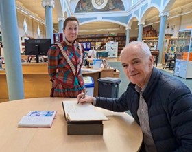 Frank Connelly from the world’s first Carnegie Library, in Dunfermline, signs Keighley Carnegie Library’s original Visitors’ book from the opening in 1904.  